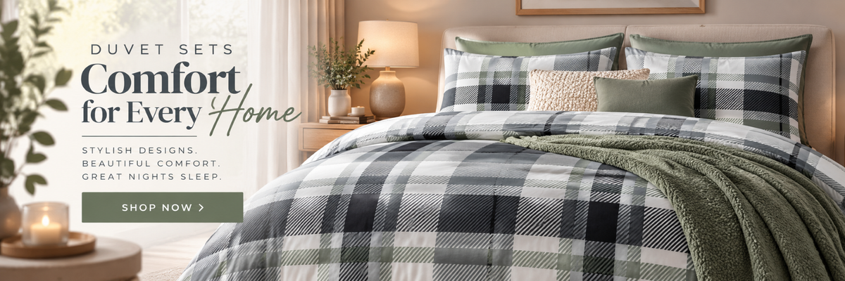 A bed dressed in a green, white, and black plaid comforter set with matching pillows and a green throw blanket, styled in a warm bedroom setting with bedside tables, lamps, and a window.